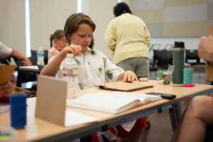Photo of children creating books out of cardboard with Jessie Gainer