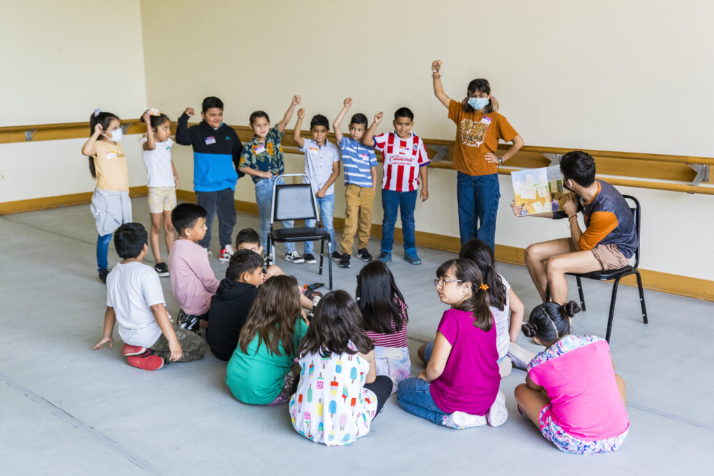 Photo of a UTeach Theatre student teaching 3rd graders 