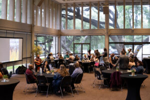 Wide view of tables of students, faculty, and guests enjoying food and conversation at the UTeach Fine Arts Spring Celebration.