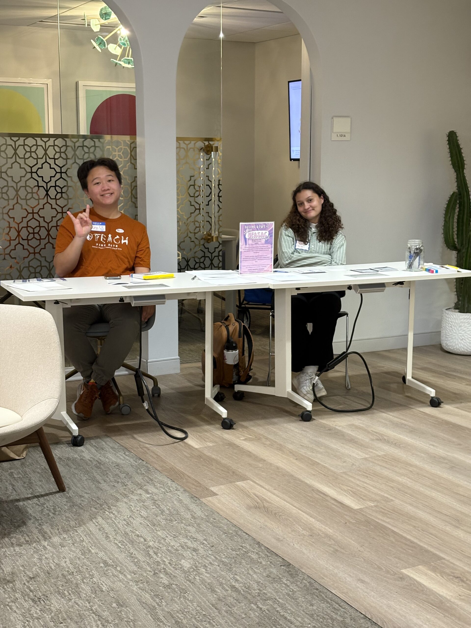 Students sitting at welcome table for event sign in.