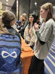 Collegiate Fair on Wednesday, January 8, 2025. Student in front of table with UTeach Fine Arts logo on tablecloth.