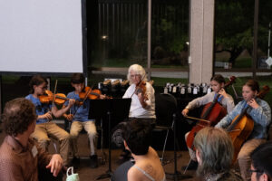 5th graders and Dr. Laurie Scott performing a strings musical performance.