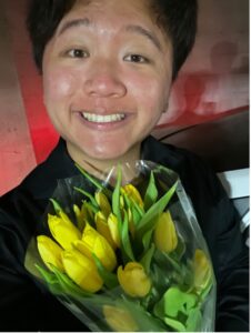 Photo of Kenneth Qu holding a bouquet of yellow tulips.