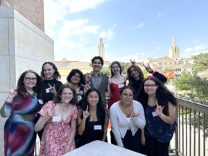 Photo of UTeach Fine Arts student Advisory Council with Roxanne Schroeder-Arce in front of the UT Tower at the 2025 Spring Celebration 