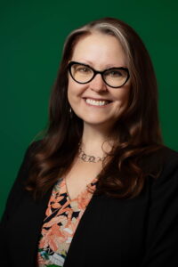 Headshot Photo of Roxanne Schroeder-Arce in front of a green background